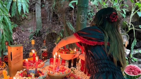 Mentora Kamily arrumando uma mesa de doces, velas e frutas em uma oferenda